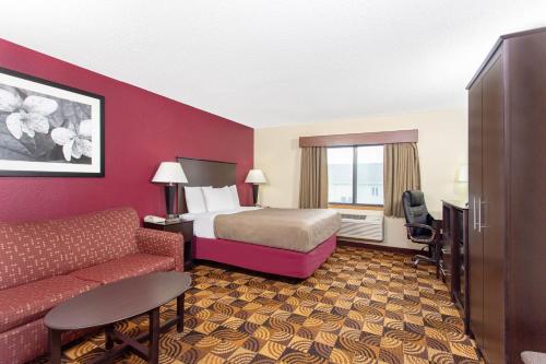 um quarto de hotel com uma cama e um sofá em AmericInn by Wyndham Elkhorn Near Lake Geneva em Elkhorn