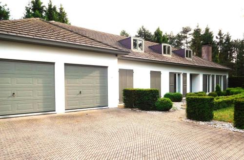a house with two garage doors on a driveway at Suite Horatio in Heusden - Zolder