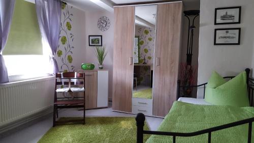 a bedroom with a green bed and a mirror at Ferienhaus Scheper in Bad Frankenhausen