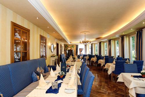 a dining room with white tables and blue chairs at Hotel-Restaurant Schmachtenbergshof in Essen