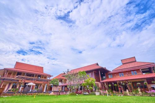 a group of houses with a green field in front at Mina Garden Villa Resort in Chiang Mai