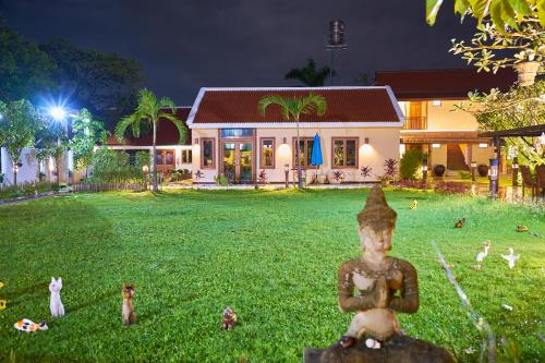 a statue in the grass in front of a house at Mina Garden Villa Resort in Chiang Mai