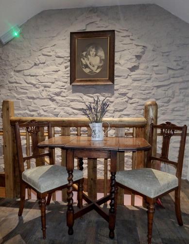 a table and chairs with a vase of flowers on it at Brecon Boutique Breaks River Run in Sennybridge