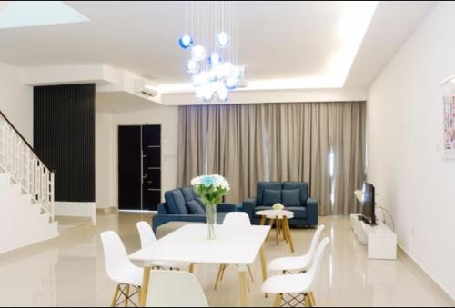 een woonkamer met een bank en een tafel en stoelen bij 4-Bedrm ensuite family friendly house near Aeon Bukit Indah in Johor Bahru