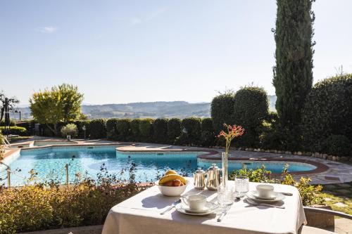 Relais Santa Chiara Hotel - Tuscany Charme في سان جيمنيانو: طاولة عليها صحن من الفواكه بجانب مسبح