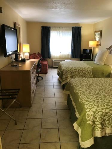 a hotel room with two beds and a flat screen tv at Days Inn by Wyndham N Orlando/Casselberry in Orlando