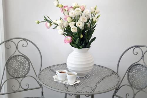a vase with flowers and two cups of coffee on a table at Barbarella Home in Naples
