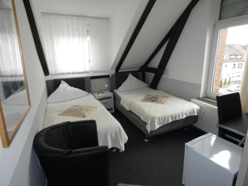 een kleine kamer met 2 bedden en een stoel bij Hotel Wolters in Bremen