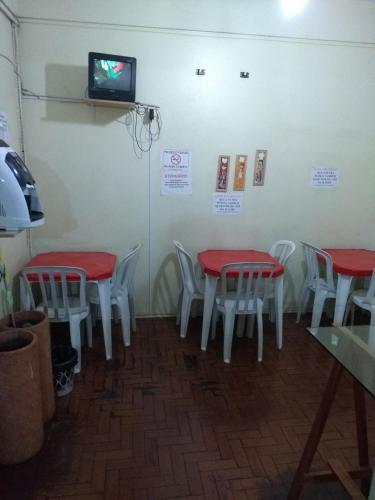 comedor con 2 mesas y sillas y TV en Hotel Santa Sara, en Ribeirão Preto
