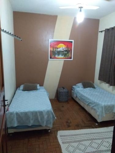 Habitación con 2 camas y una pintura en la pared. en Hotel Santa Sara, en Ribeirão Preto