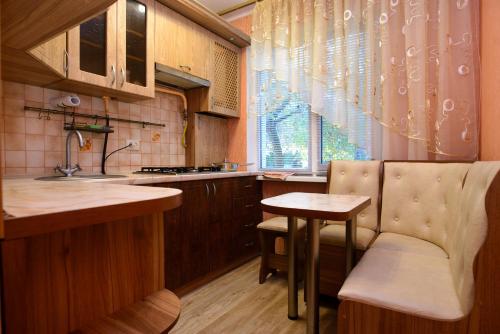 eine Küche mit einem Waschbecken, einem Tisch und einem Fenster in der Unterkunft Апартаменты Deluxe in Tscherkassy