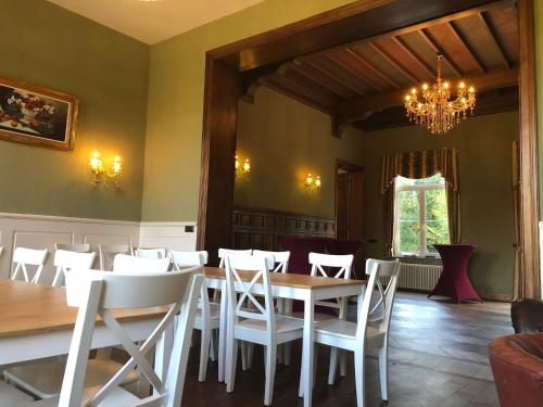 a dining room with a table and white chairs at Kasteel B&B Sint-Bartel in Geraardsbergen