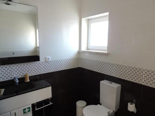a bathroom with a toilet and a sink and a mirror at T2 Baleal in Peniche