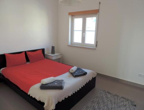 a bedroom with a bed with red pillows and a window at T2 Baleal in Peniche