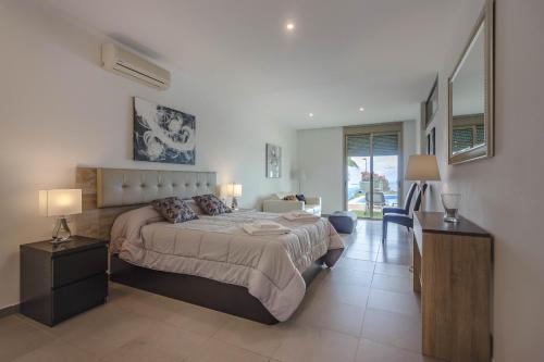 ein Schlafzimmer mit einem Bett und einem Schreibtisch mit zwei Lampen in der Unterkunft Villa Isabella, Luxury Villa with Heated Pool Ocean View in Adeje, Tenerife in Adeje