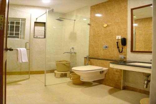 a bathroom with a toilet and a glass shower at Raya's Grand in Kumbakonam