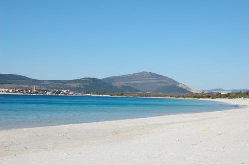 a beach with blue water and mountains in the background at Gardenia Casa Vacanze in Alghero
