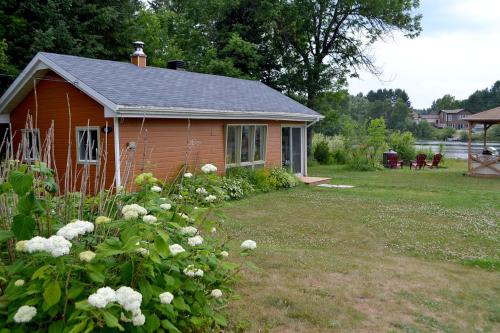 a small red house with a yard with flowers at Les 4 chalets - Le 605 in Lac-Saint-Paul