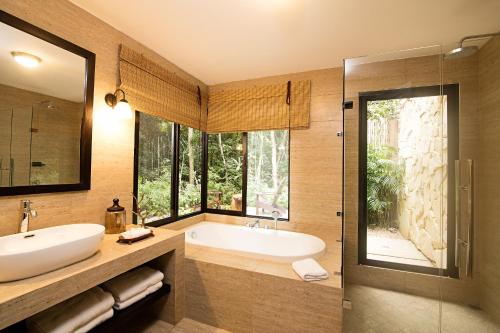 y baño con bañera, lavamanos y ducha. en Hotel Jungle Lodge Tikal, en Tikal