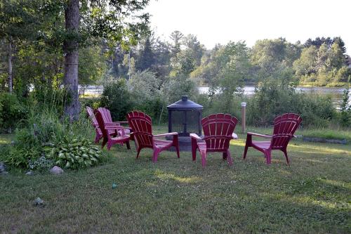 a group of red chairs sitting in the grass at Les 4 chalets - Le 605 in Lac-Saint-Paul