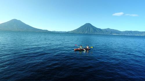 two people in a boat on a large body of water at Atitlan Sunset Lodge in Santa Cruz La Laguna