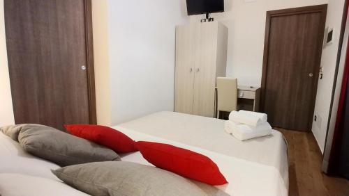 a bedroom with a white bed with red pillows at B&B Il Campanile in Sciacca
