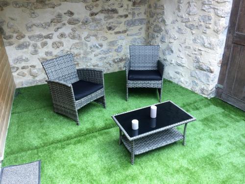 two chairs and a table in a room with green grass at La maison bleue in Nogent-sur-Seine