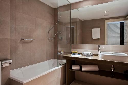 a bathroom with a tub and a sink and a bath tubermott at Exe Moncloa in Madrid