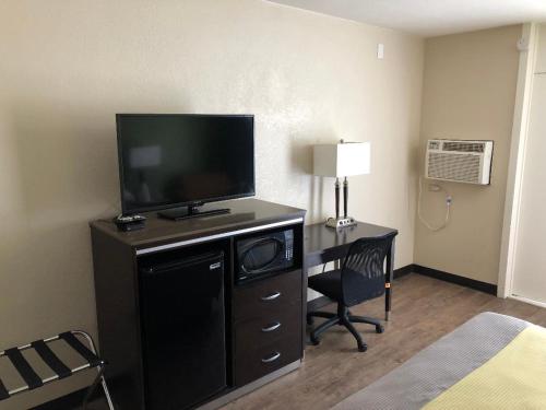 a hotel room with a desk with a television and a bed at Inn Of Long Beach in Long Beach