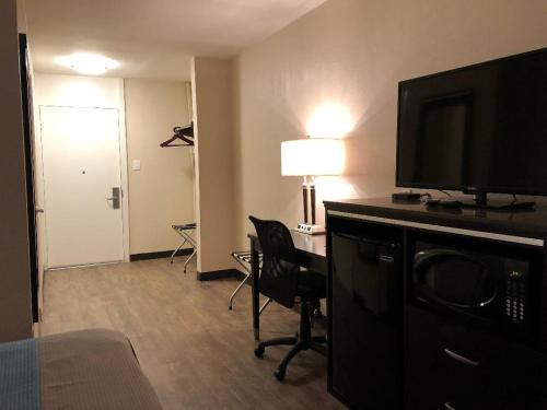 a hotel room with a desk with a television and a room at Inn Of Long Beach in Long Beach
