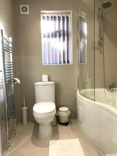 a bathroom with a toilet and a shower and a tub at Glaisdale Apartment in Wolverhampton