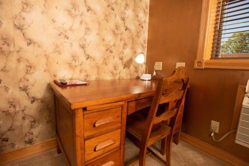 a wooden desk with two chairs in a room at Blue Spruce Motel in Massena