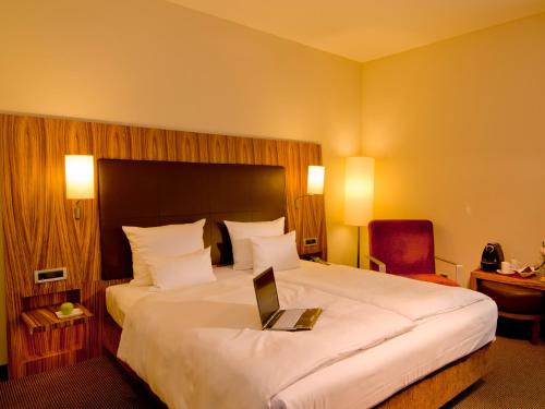 a hotel room with a bed with a laptop on it at ACHAT Hotel Regensburg Herzog am Dom in Regensburg