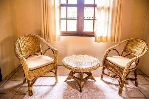 two wicker chairs and a table in a room at Hotel Pousada da Lagoa in Garopaba