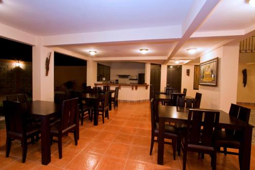 a dining room with tables and chairs and a bar at Hotel El Cerro in Liberia