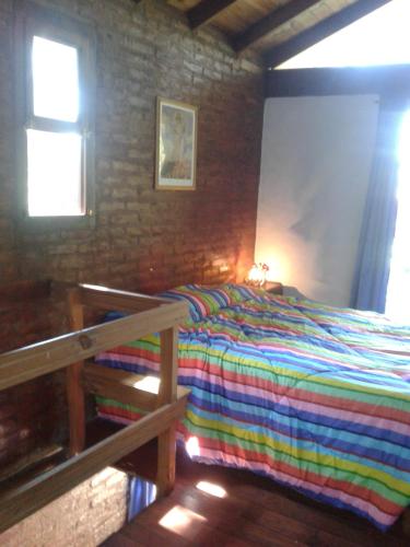 1 dormitorio con 1 cama con una manta a rayas de colores en Cabañas Mar Azul en Balneario Mar Azul