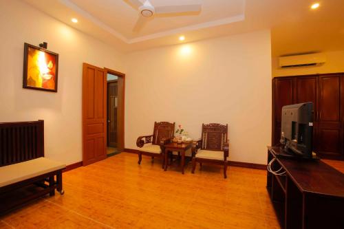 a living room with a tv and a table and chairs at Hoi An Garden Villas in Hoi An