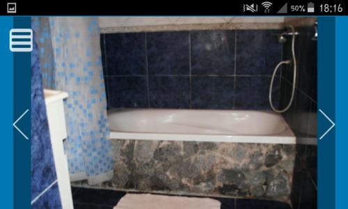 y baño con bañera y pared de azulejos azules. en Cabañas Mar Azul en Balneario Mar Azul