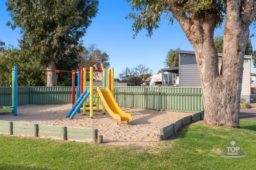 a playground with a yellow slide next to a tree at Esperance Bay Holiday Park in Esperance