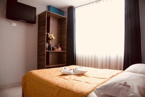 a bedroom with a bed with a tv and a window at Hotel Jorge Chavez in Trujillo