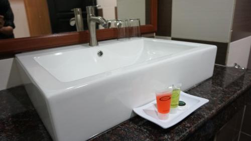 a white sink with a drink on a plate at De Baron Resort in Kuah