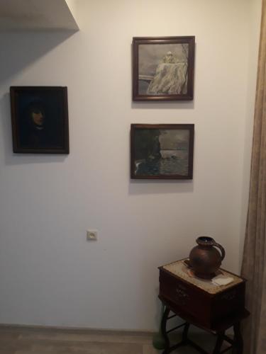 a wall with three paintings and a table with a vase on it at Merabi Guest House in Makhinjauri