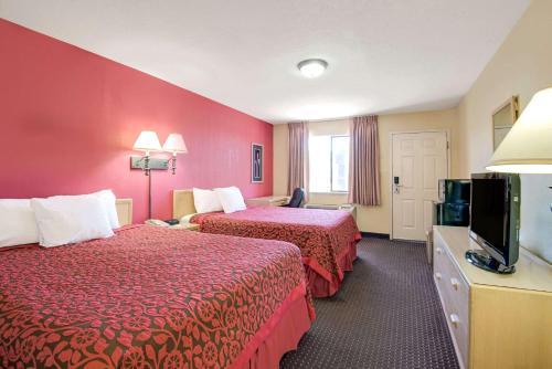 a hotel room with two beds and a flat screen tv at Days Inn by Wyndham East Albuquerque in Albuquerque