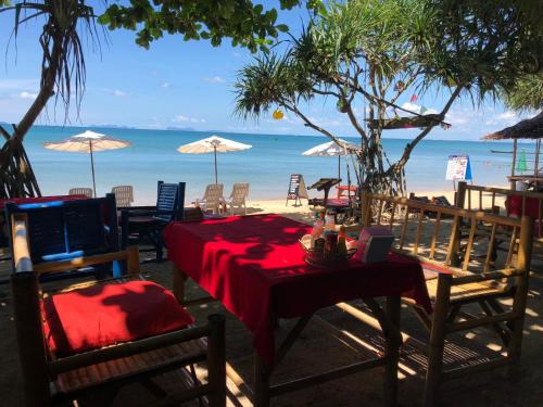 a table and chairs on a beach with the ocean at Breizh Cape Beach Bungalows in Ko Lanta