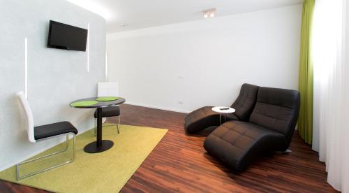 a living room with a couch and a chair and a table at Hotel Barth in Kaiserslautern