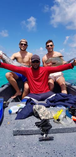 three men sitting on a boat with their arms in the air at Posada Ashanty in Providencia