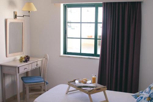 una stanza con un letto, una scrivania e una finestra di Dunas do Alvor - Torralvor ad Alvor
