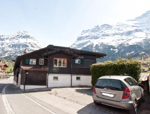 a car parked in front of a house with mountains at 2BR apartment close to ski area and Jungfrau train in Grindelwald