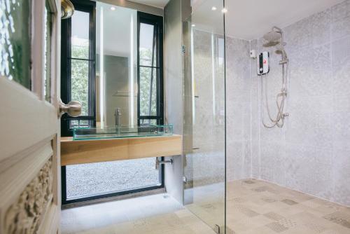 a bathroom with a glass shower with a sink at Sabaiday Guesthouse Nimman in Chiang Mai