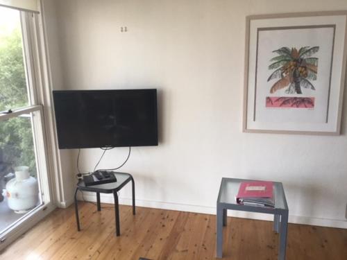 a living room with a flat screen tv and a table at Dutchies Beachside Retreat in Nelson Bay